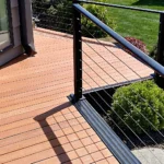 A modern backyard deck built with composite decking and a metal cable railing.